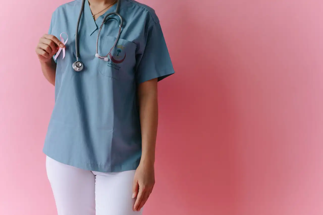 Professionnelle de santé en blouse bleue avec stéthoscope tenant un ruban rose de sensibilisation