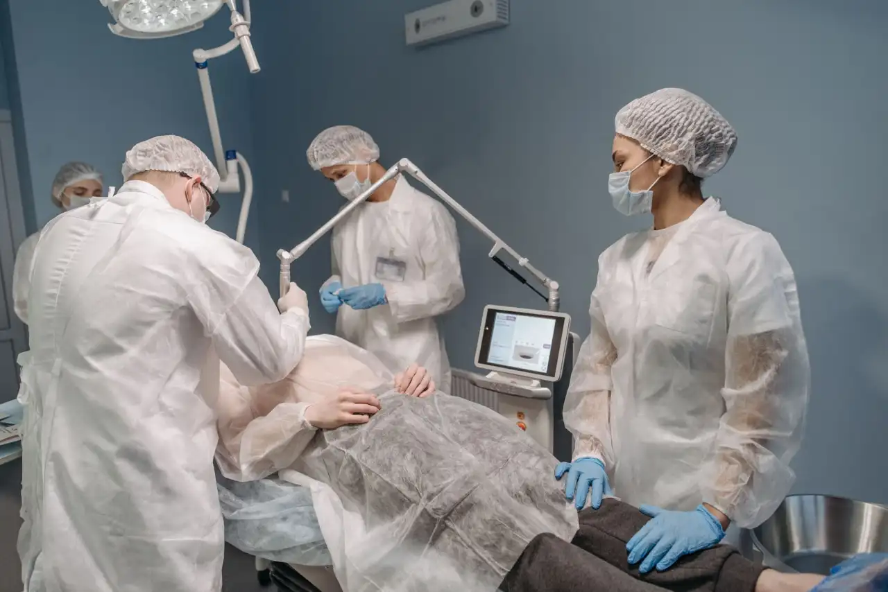 Équipe médicale en tenue stérile examinant un patient dans un cabinet médical équipé de technologie médicale