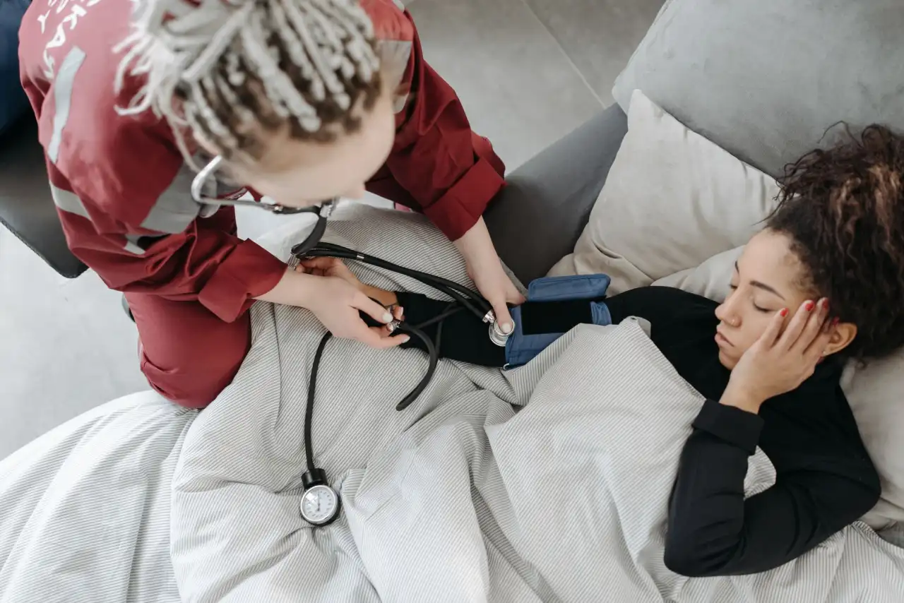 Médecin en blouse rouge examinant un enfant avec un stéthoscope, mère présente à ses côtés
